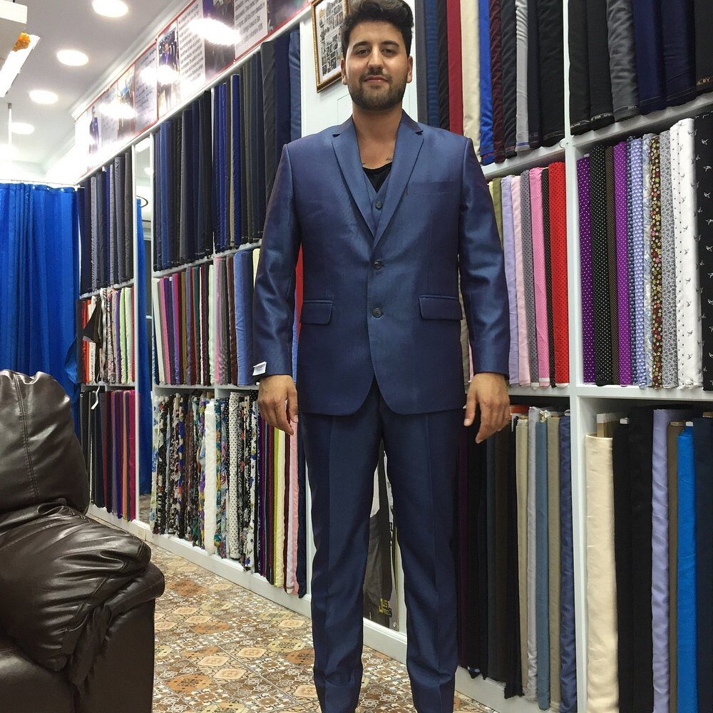 A client in his finished three-piece blue suit in front of the cloth wall